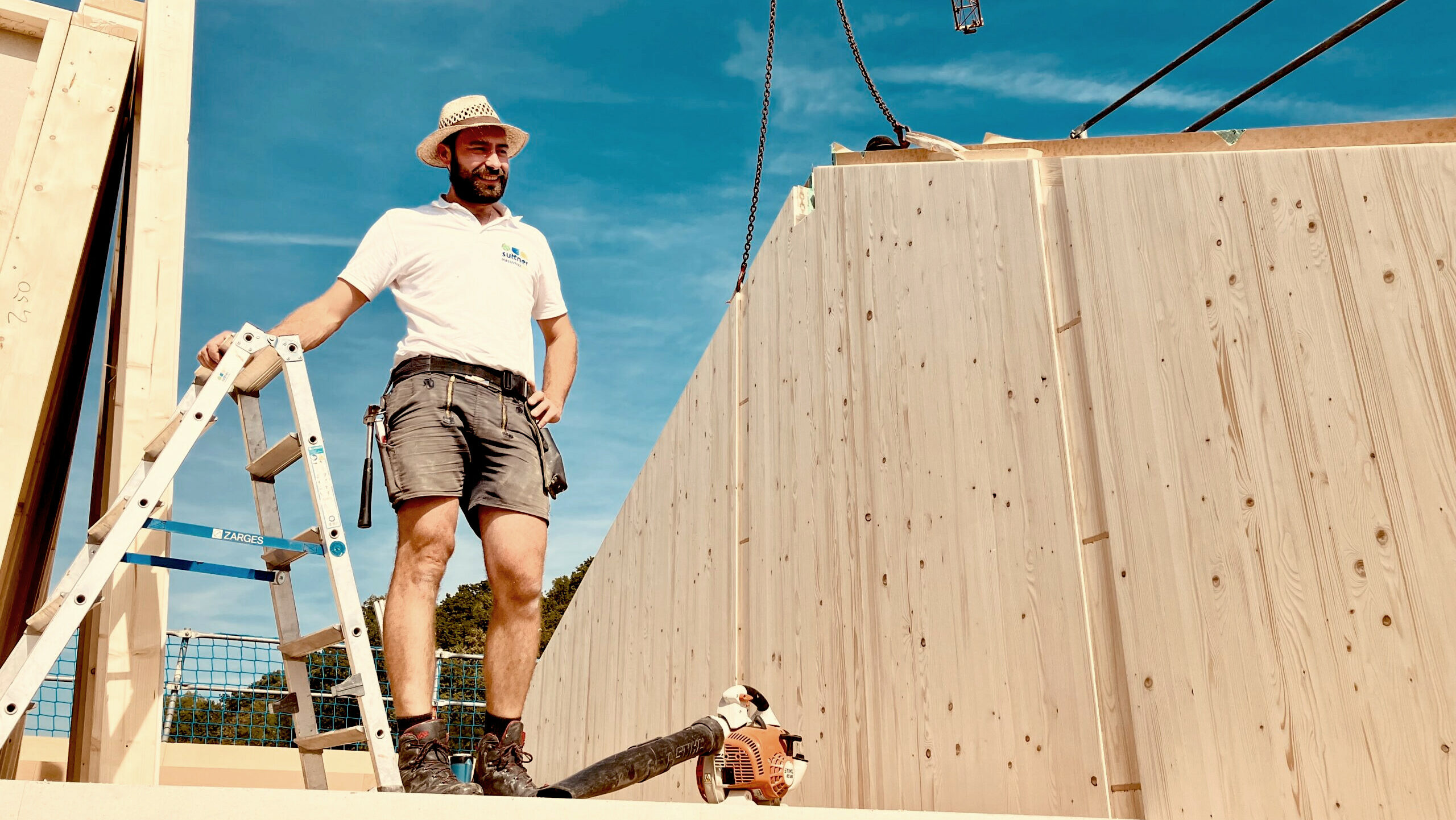 Zimmerer bei Aufstellen von Massivholzhaus auf Baustelle