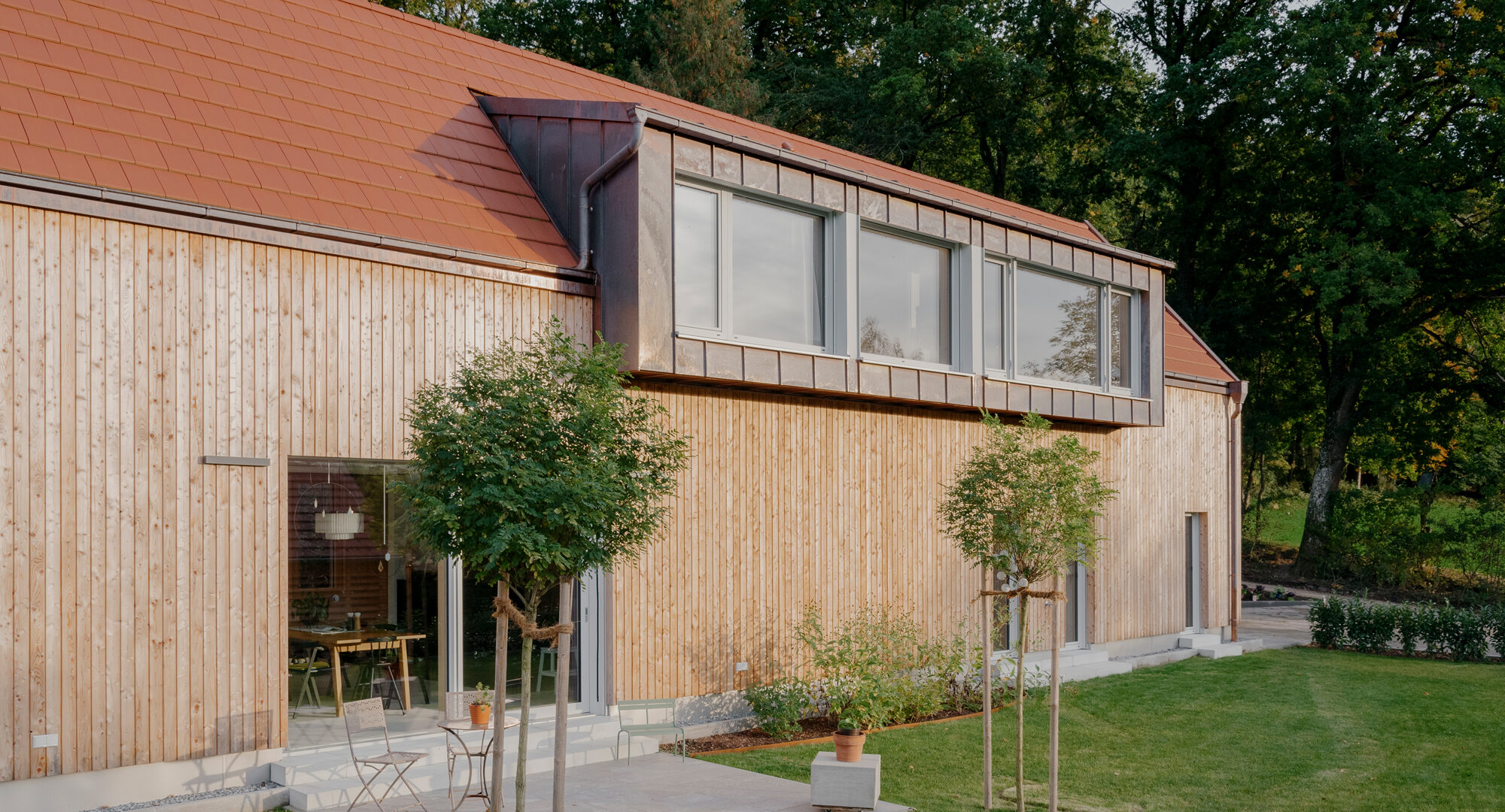 Massivholzhaus Schi_N mit vertikaler Holzfassade, Terasse und Dachgaube