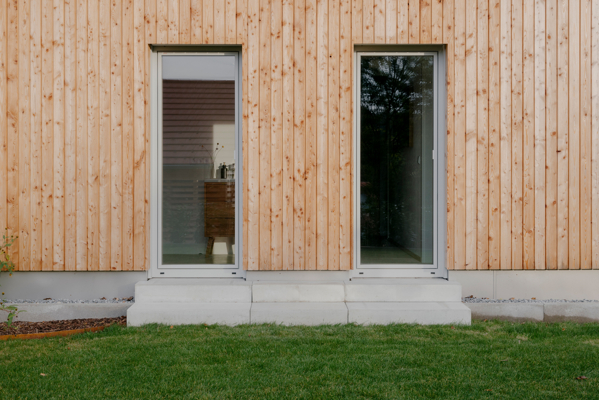 Fenstertüren in Massivholzhaus Schi_N mit vertikaler Holzfassade