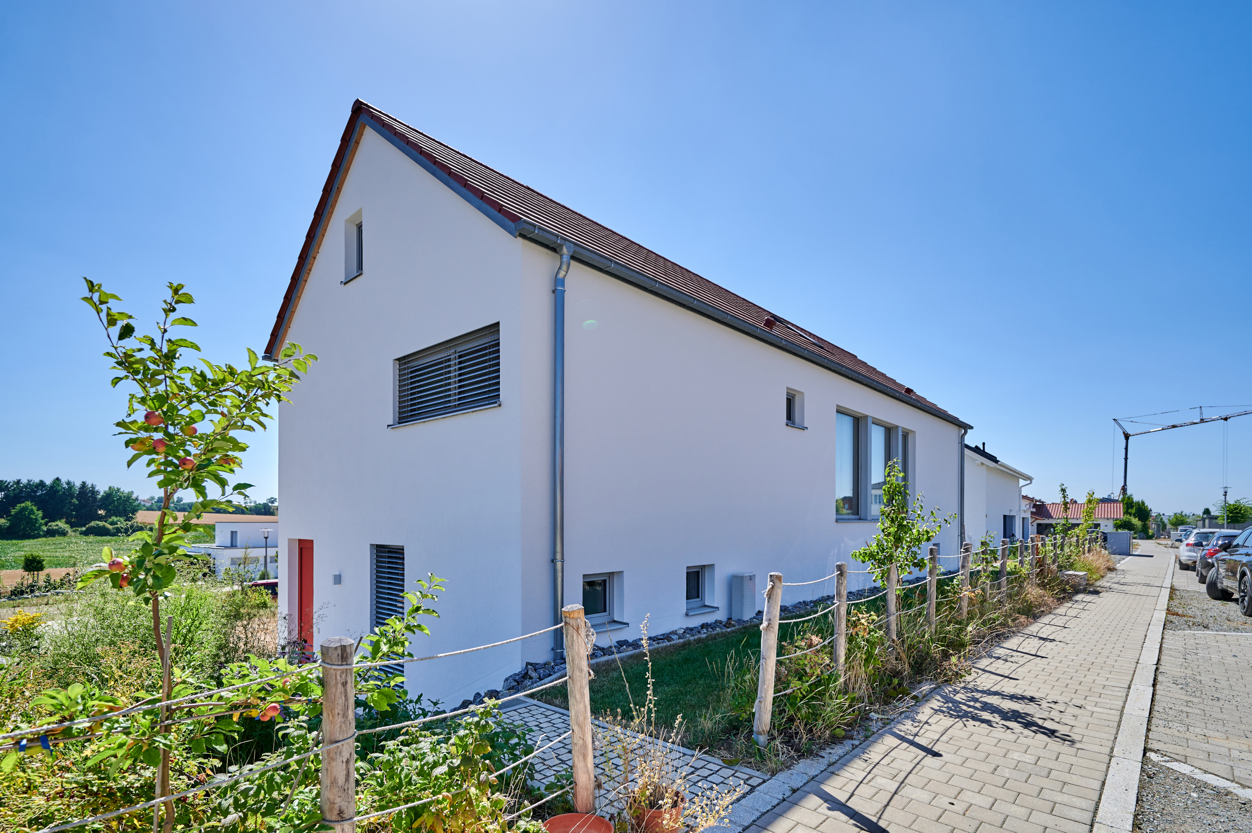 Giebelseite Massivholzhaus We_S mit Putzfassade mit roter Haustür