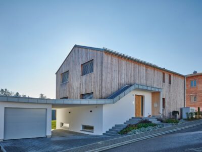 Massivholzhaus Su_H mit vertikaler Holzfassade und Garage