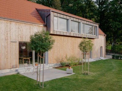 Massivholzhaus Schi_N mit vertikaler Holzfassade, Terasse und Dachgaube