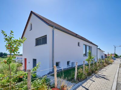 Giebelseite Massivholzhaus We_S mit Putzfassade mit roter Haustür