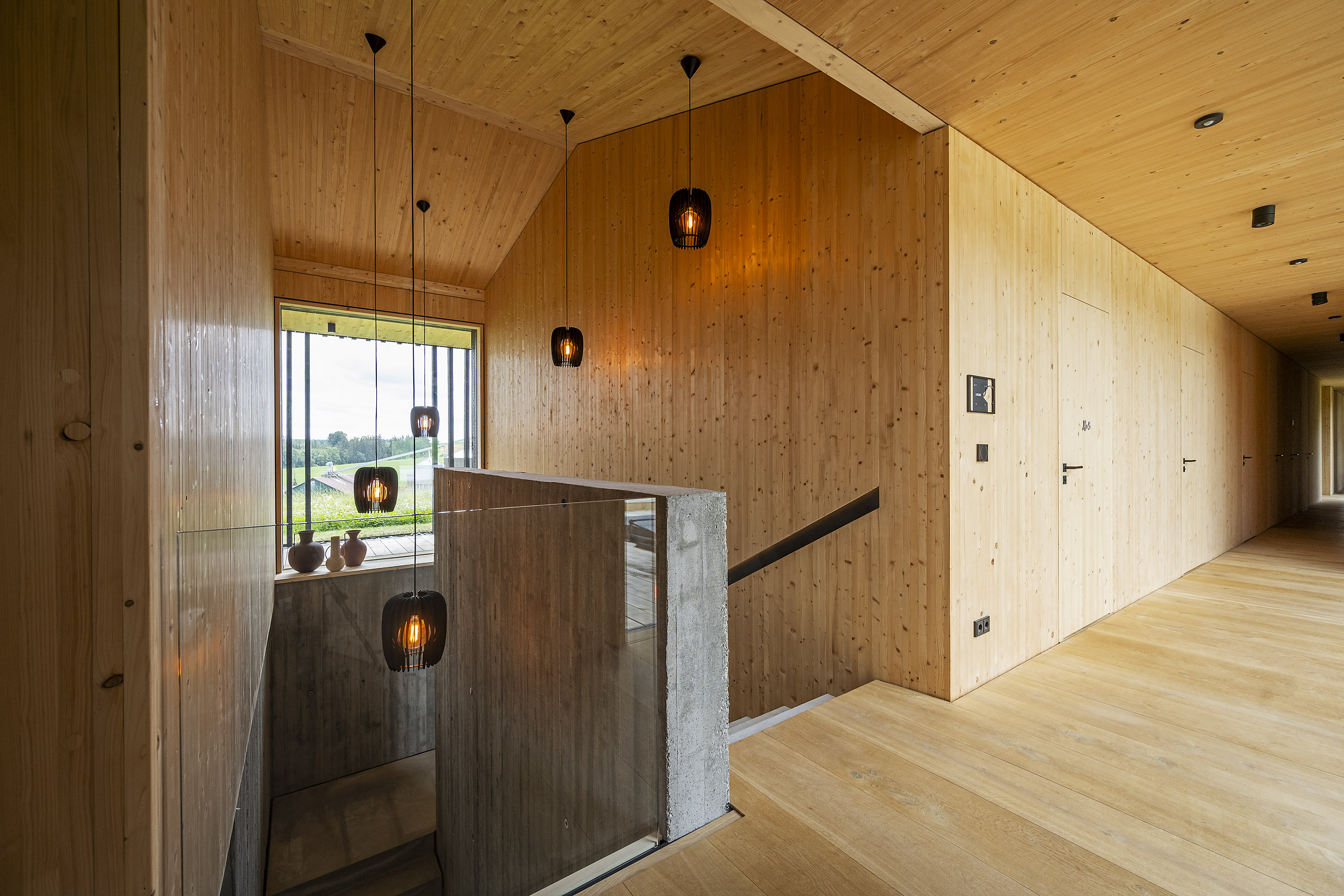 Treppenhaus mit bündigen Türen und Sichtbeton sowie viel sichtbares Dübelholz